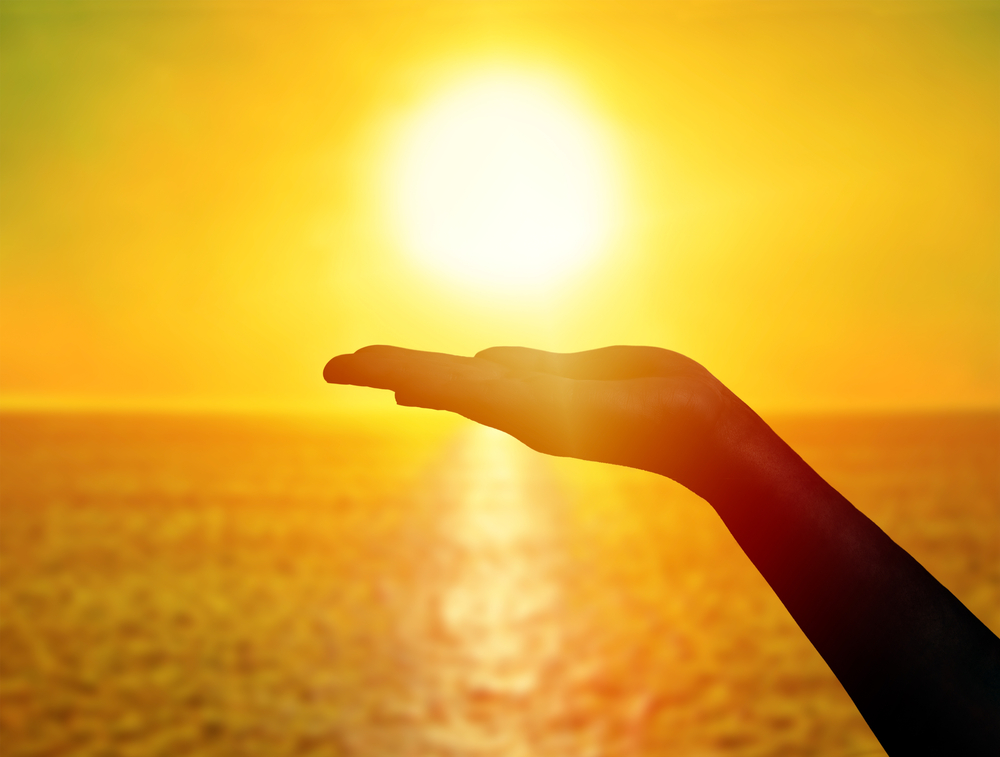 Woman,Hand,Holding,Sun,At,Sunset,On,The,Beach